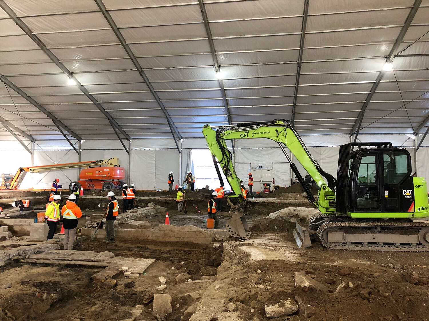 Even under the large tent structure, there is room for a mechanical excavator to operate